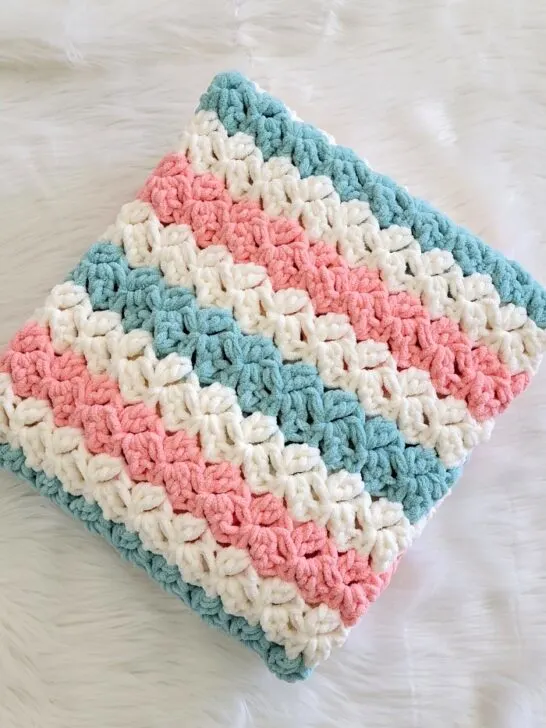 Fast crochet blanket pattern finished in peach, blue and cream colors folded neatly