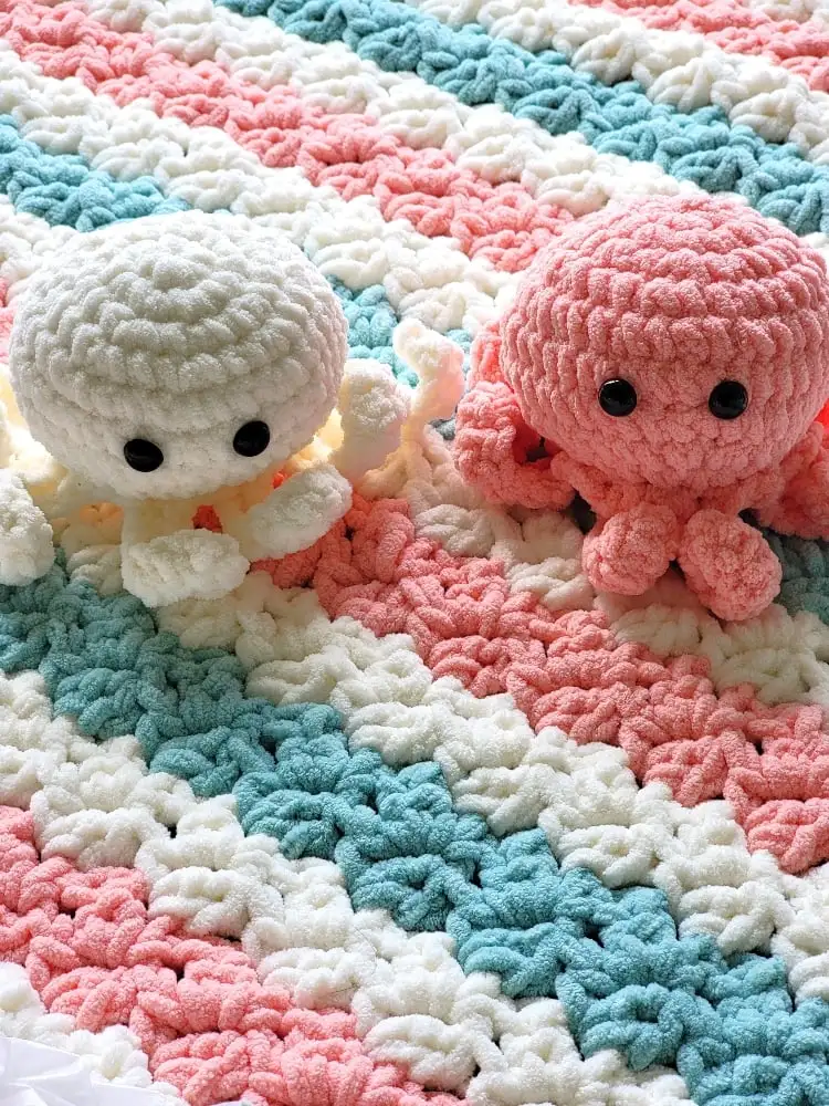 Crochet octopus in cream and blue color placed on matching blanket