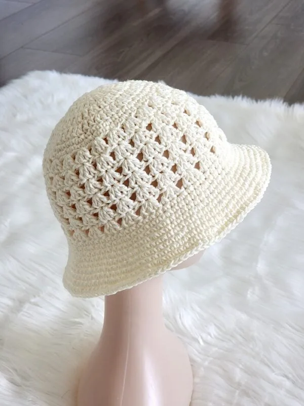 crochet bucket hat pattern in cream color on a mannequin head 