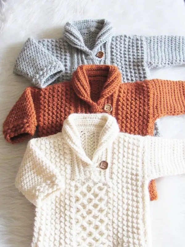 3 finished crochet baby sweaters in gray, burnt orange and gray colors