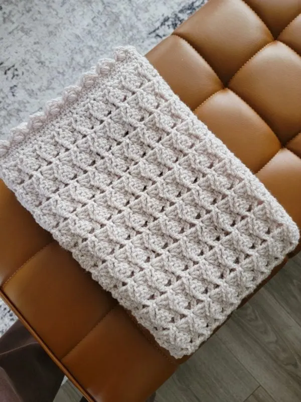 Crochet afghan folded and placed on a leather bench