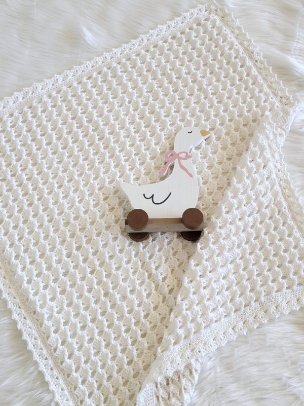 White crochet blanket with a duck toy placed on it.
