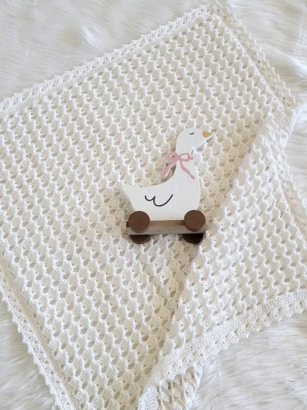 White crochet blanket with a duck toy placed on it.