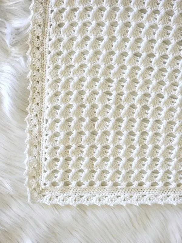 Closeup of the corner of white gender neutral blanket showing stitch pattern and border