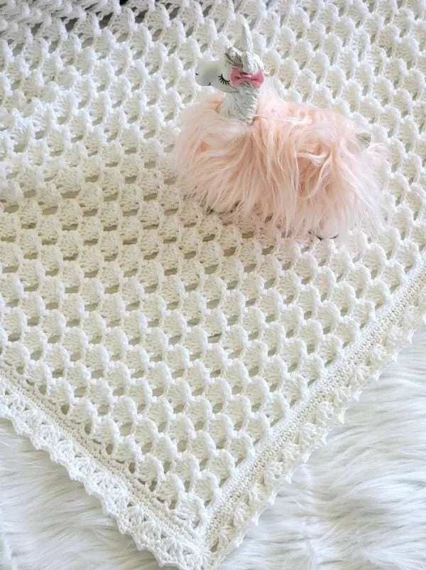 White blanket with a fluffy unicorn toy