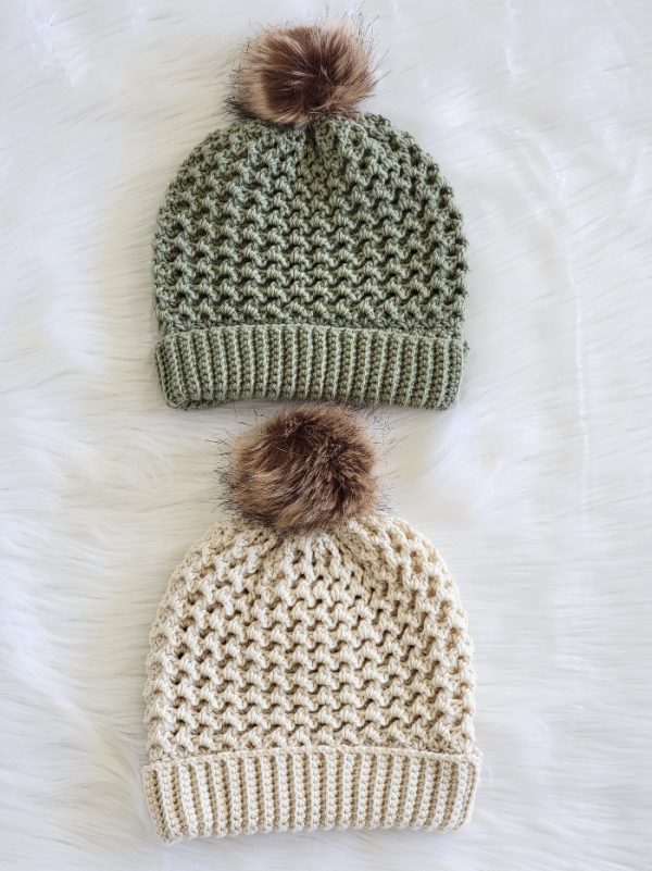 green and cream colored beanies with fur pom poms