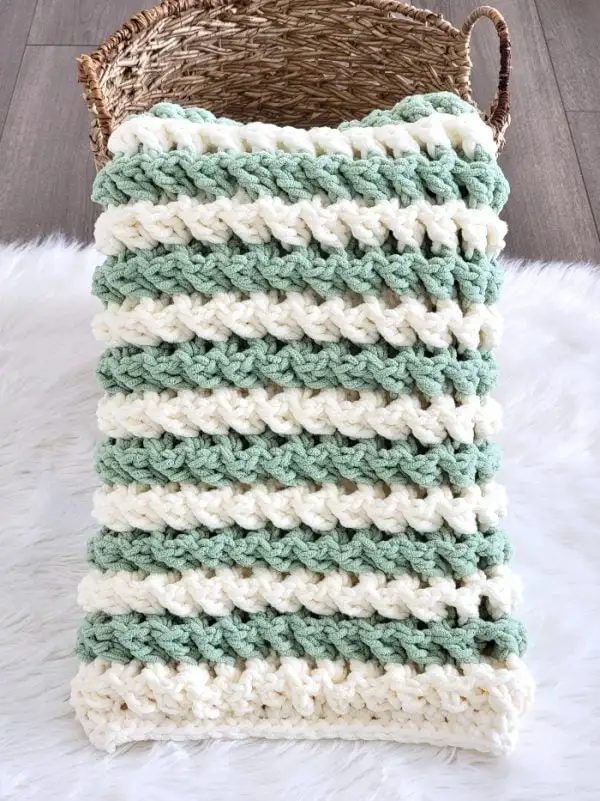 crochet chunky blanket in cream an sage color displayed in a basket