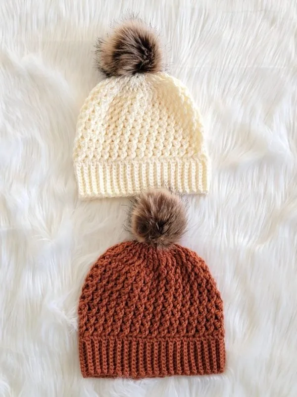 2 crochet beanies in cream and burnt orange colors with fur pom pom