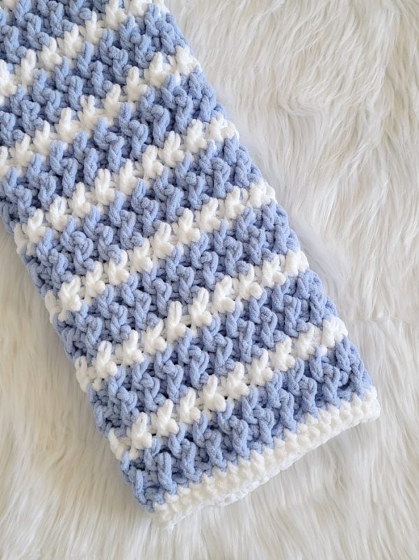 Folded blue striped blanket laid on wite fur fabric
