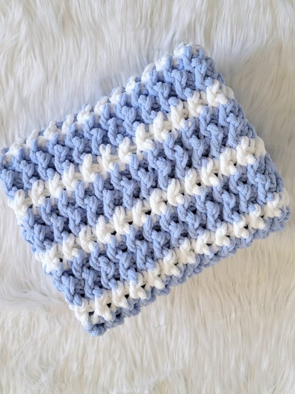 Folded blue crochet blanket with white stripes