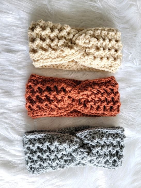 3 crochet twist headbands in cream, orange and gray displayed on fur fabric