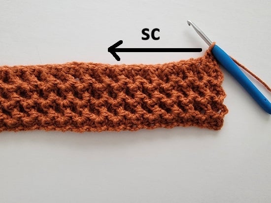 Shows the orange color headband with a blue crochet hook