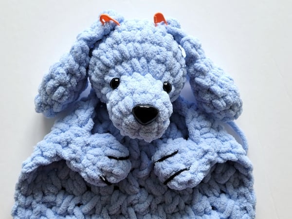 Orange stitch markers holding the ears on the head