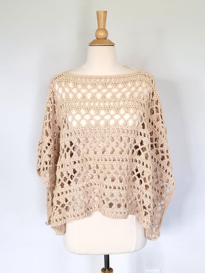 crochet lacy summer poncho in cream color modeled on a mannequin
