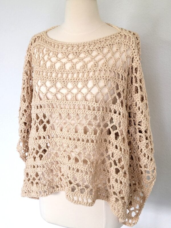 Side view of finished lacy crochet poncho on a mannequin