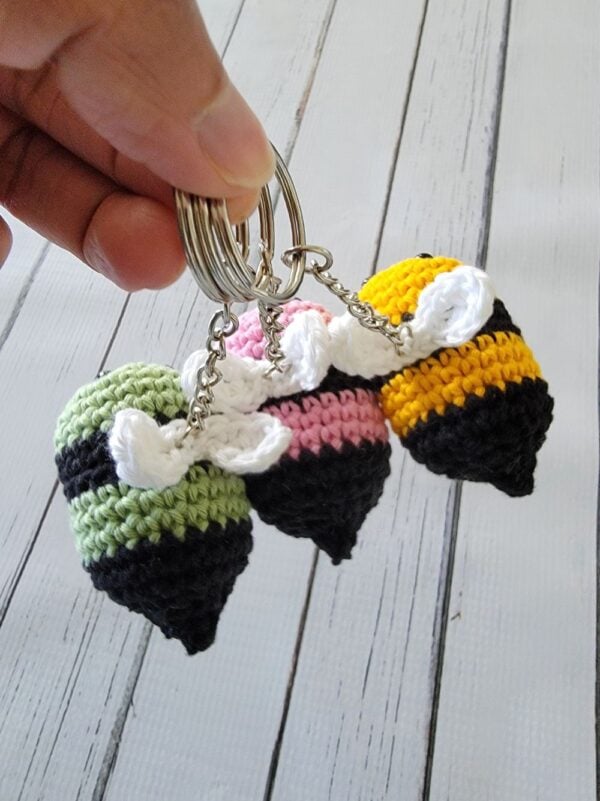 Top view of bee crochet keychains in colors yellow, pink and green