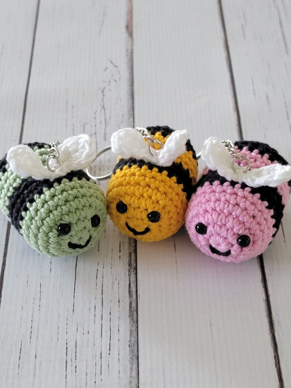Crochet bee keychain pattern finished in yellow, pink and green colors