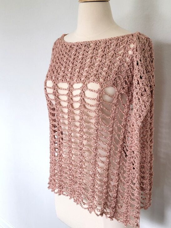 Crochet poncho for women in peach color modeled on a mannequin