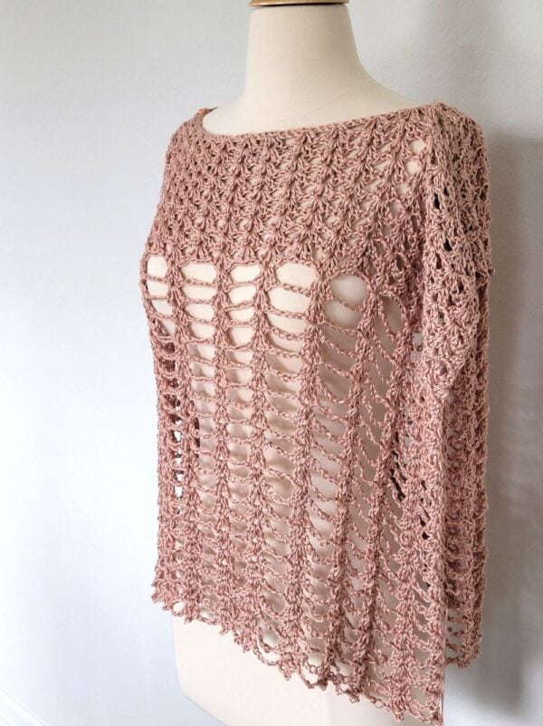 Crochet poncho for women in peach color modeled on a mannequin