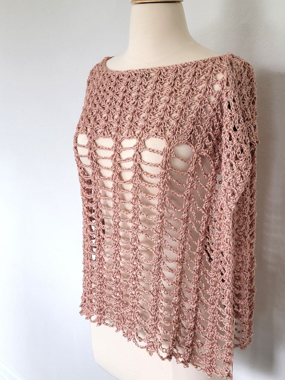 Crochet poncho for women in peach color modeled on a mannequin