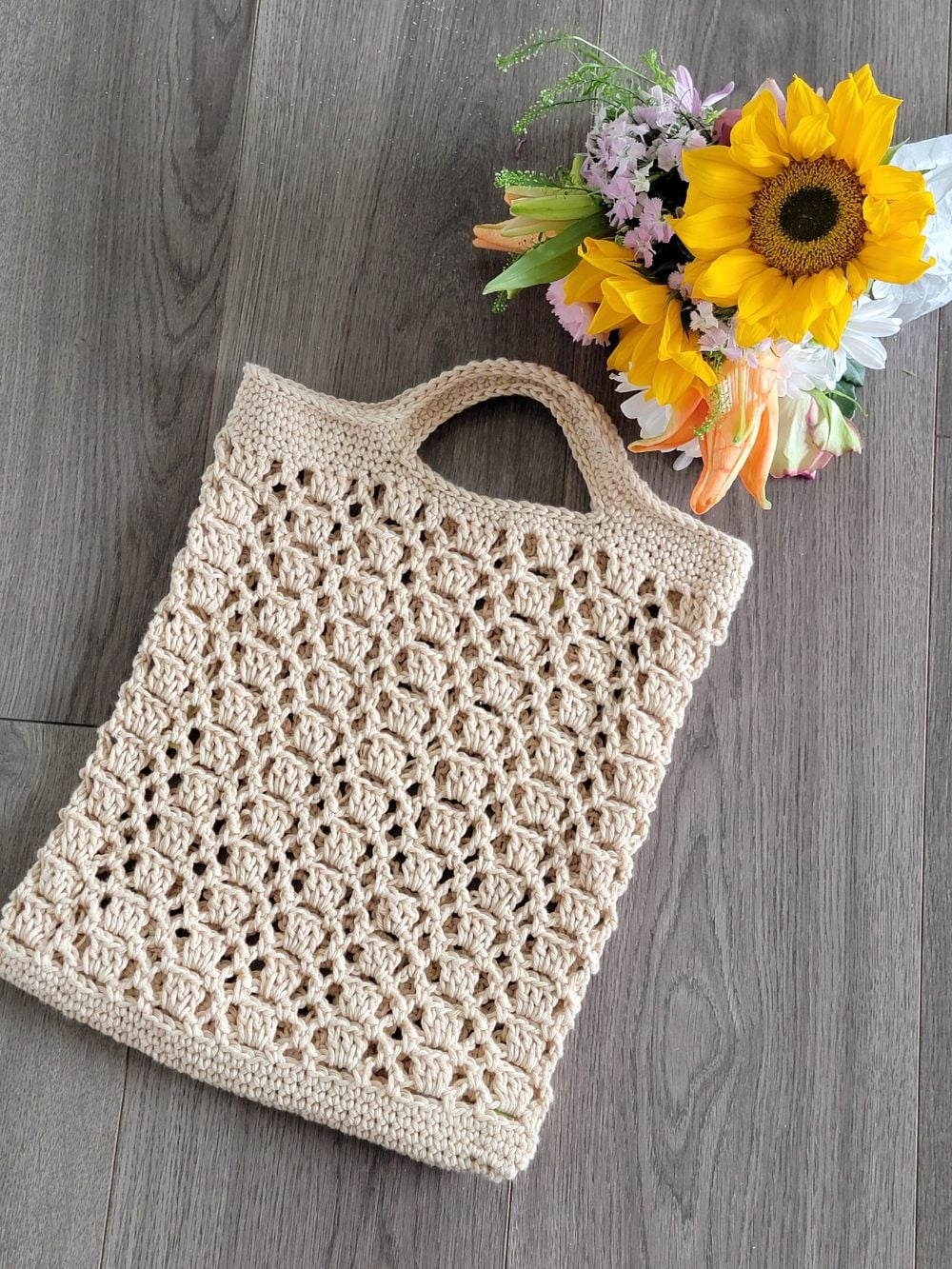 Crochet produce bag displayed with a bunch of flowers
