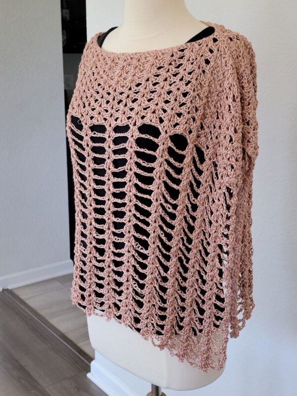 Side view of crochet poncho worn over a black tank top