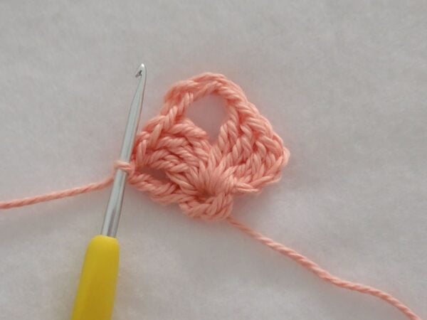 Row 1 of the crochet bandana showing the first shell stitch worked into the starting ring with chain loops on each side.