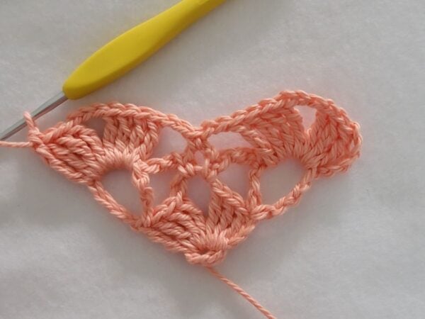 Row 3 of the crochet bandana showing five shell stitches joined with chain loops.
