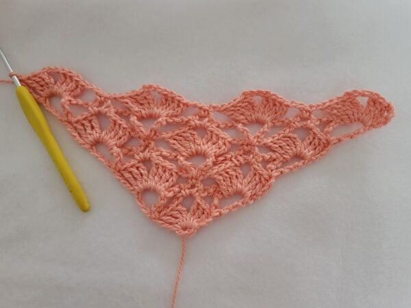 Row 7 of the crochet bandana displaying the repeating lace shell pattern as the triangle continues to expand.