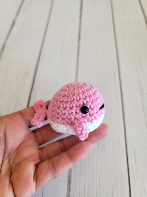 Pink crochet whale held in hand