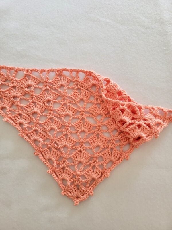 Peach crochet bandana laid flat on a white background, featuring an airy shell stitch lace pattern with long tie straps.