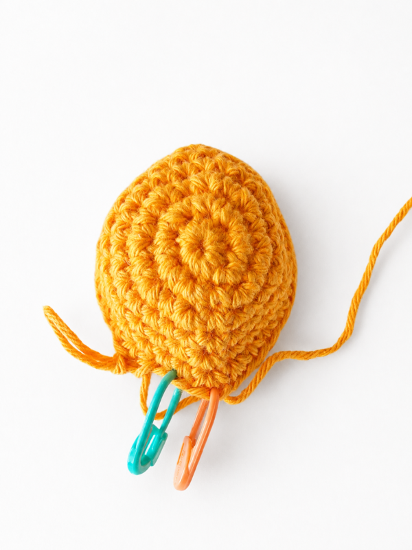 Crochet whale body worked in blue yarn with stitch markers placed at the opening before attaching the fins.