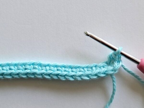 First row of the crochet headband worked along the foundation chain with the hook in the last stitch.