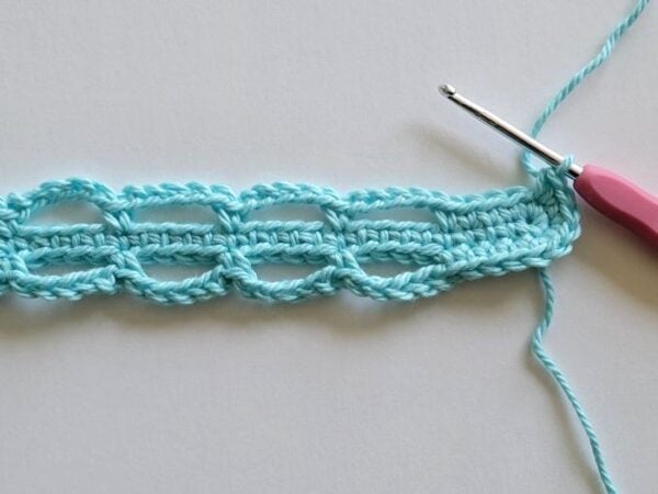 Crochet headband in progress with chain loops worked along both sides of the center row.