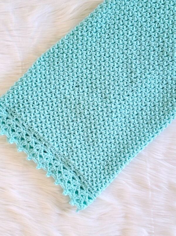 Folded aqua crochet baby blanket showing the simple textured stitch pattern and pretty lace edging.