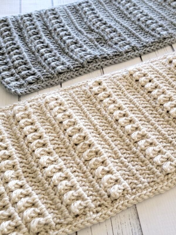 Close-up of cream and gray unisex or men's crochet scarves with raised textured stitches.