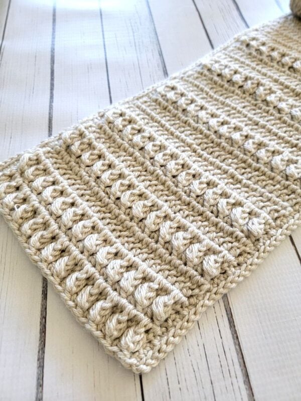 Close-up of a cream men's crochet scarf showing rows of raised textured stitches
