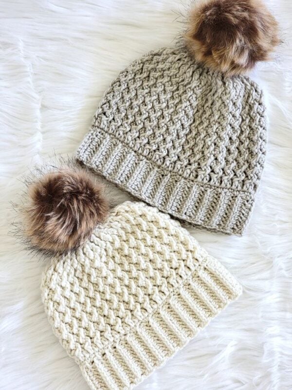 Cream and gray crochet winter hats featuring raised textured stitches and brown faux fur pom poms.