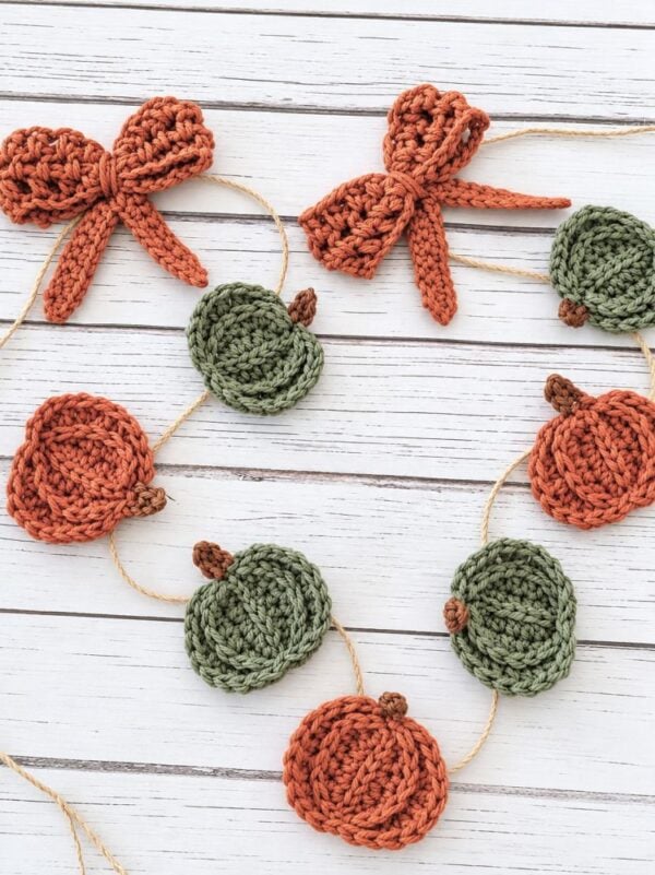 Close-up of crocheted orange bows and textured pumpkins strung together with twine.