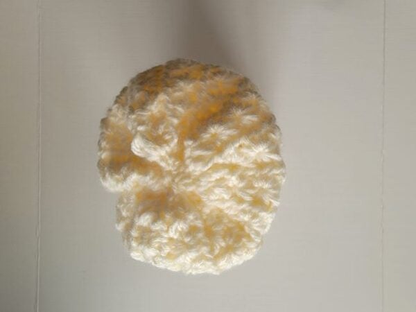 Bottom view of the crochet pumpkin with the opening tightly gathered closed.