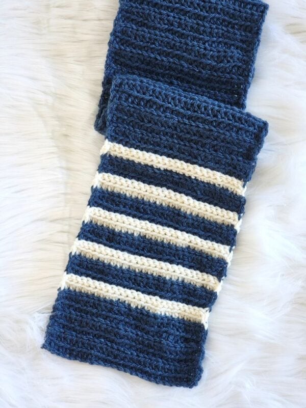 Navy blue crochet scarf with cream stripes and a textured ribbed stitch pattern.