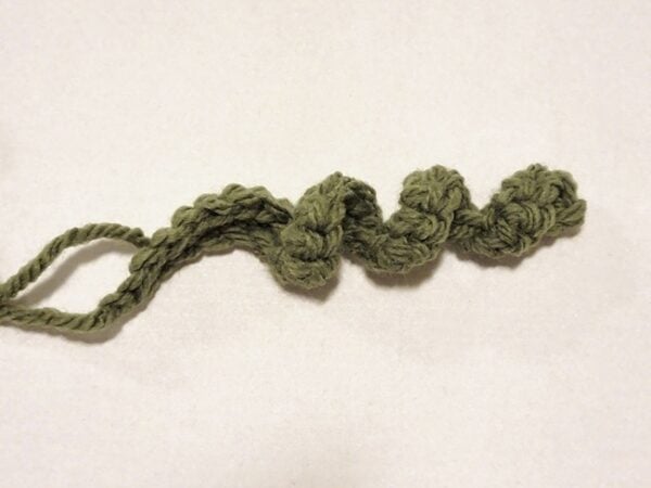 Green crocheted curly vine with a yarn tail, ready to attach to the crochet pumpkin.