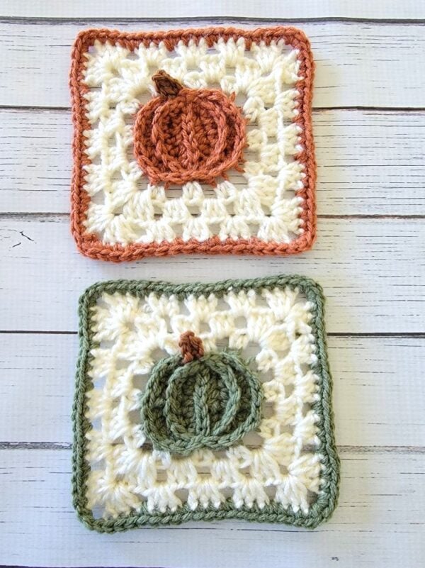 Two square crochet pumpkin coasters featuring raised orange and sage green pumpkins, cream textured stitches, and matching borders.