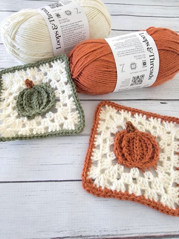 Orange and green crochet pumpkin coasters with cream granny square backgrounds, displayed alongside matching yarn skeins.